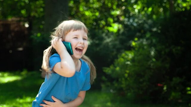 Happy, cheerful little girl, child talking on her smartphone, speaking through mobile phone, bursting out laughing out loud, hearing someting funny Happiness, loud genuine laughter, true joy portrait