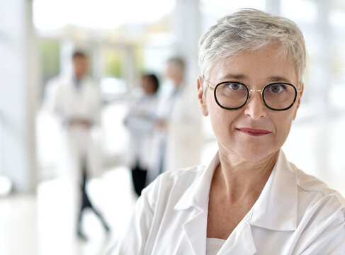 Portrait of smiling mature woman doctor standing in hospital hallway