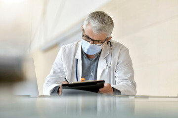 Portrait of doctor working in office with face mask