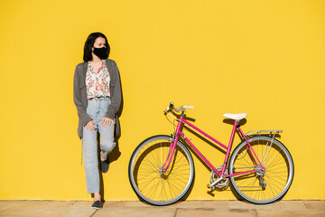 girl with mask in a yellow wall next to her bike