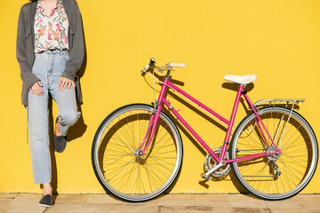 unrecognizable woman in a yellow wall with a bike