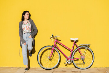 smiling girl in colorful yellow wall with a bike