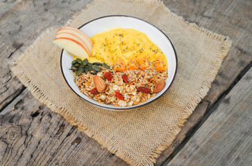 Healthy food smoothie bow Fresh fruit smoothie is good for the body.  with mango, banana, nuts, seeds, papaya, almonds, sunflower  and homemade granola and apple for healthy ingredients placed on the 