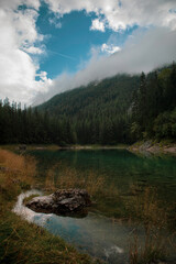 Fototapeta na wymiar green clear lake with forest and beautiful sky in tirol Austria