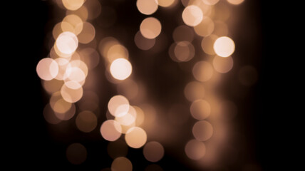 Beautiful festive bokeh on a black background golden circles, light night bokeh effect, deflated. Festive postcard, night view.