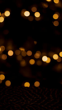 Beautiful festive bokeh on a black background golden circles, light night bokeh effect, deflated. Festive postcard, night view.