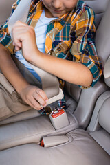 Cropped view of boy locking safety belt in auto