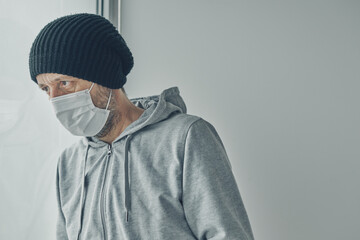 Depressed Covid-19 patient infected with coronavirus looking out the window of his home quarantine