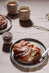 Cinnamon swirl brioche or Cinnamon roll bun and cups of cocoa on greige linen tablecloth. Homemade baked swedish cinnamon roll. Kanelbullar. Cozy winter breakfast