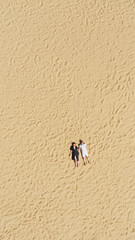 Fototapeta na wymiar Aerial view of a young couple lying on the white sand. man and woman spend time together and travel through the desert
