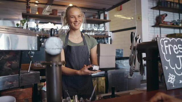 Hand of customer holding payment card close to electronic payment machine while paying for food in cafe