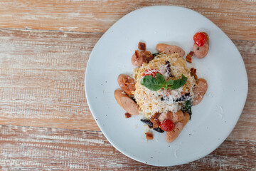 Spicy sausage spaghetti. Spicy spaghetti or Sausage spaghetti. Homemade Spicy Spaghetti with cheese on wooden table. Spaghetti with homemade sausage, hot and spicy with basil leave.