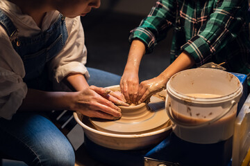 a young mother with a charming son in a pottery workshop sculpting a vase