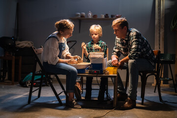a family of mom, dad and son spend their free time behind a potter's wheel in the workshop