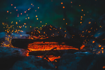 Vivid smoldered firewoods burned in fire closeup. Atmospheric background with orange flame of...