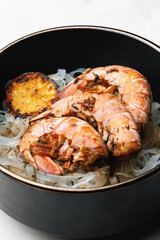 Asian food: rice noodles with prawns and herbs in a bowl. Soy sauce with garlic, ginger and lemon.