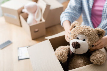 Cropped view of volunteer putting soft toy in carton package in charity center