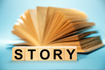 Open book and Wooden cubes with the abbreviation STORY