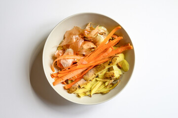 food waste from domestic kitchen, cleaning from vegetables onions potatoes and carrots in a plate on a white table background. sorting of household food waste