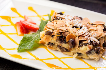 chocolate cake with creamy stuffing, garnished with planed almonds, mint and strawberries