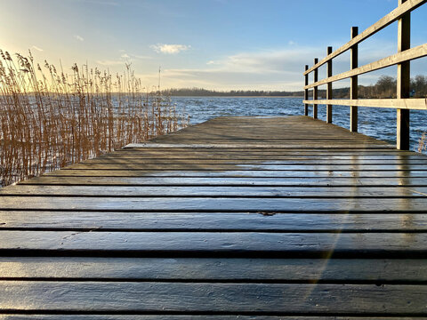 Beautiful autumn seascape sunset view with a wooden jetty, reed, horizon and sky.