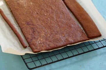 Brown gingerbread house cookie pieces drying on a rack