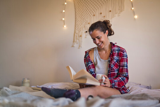Smiling woman reading book in pyjamas