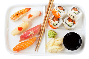 Top view of sushi served on a white plate with chopsticks. Studio photo isolated on white background. Selective focus on object. Bright light setting.