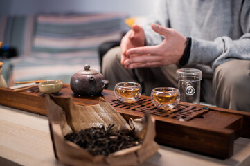 Close-up of the chinese tea ceremony ritual. Hands pour hot water into special vessels on a bamboo board