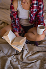 Woman reading book on bed in pyjamas