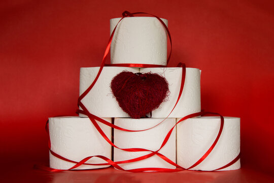 Covid-19 Toilet Paper Christmas Tree Wraped In Red Ribbon  On Red Christmas Background With Red Heart