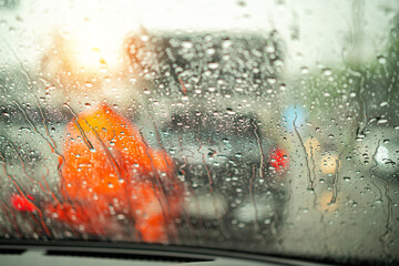 Fototapeta na wymiar Street in the heavy rain. Water drops or rain in front of mirror of car on road or street. Driving in rain. Blurred background.