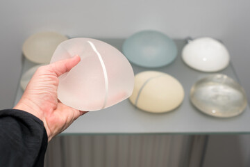 Female hand touching silicone implants for breast augmentation. Cosmetic plastic surgery....