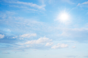 The sky is full of clouds floating around, both small and large, the sun is shining brightly