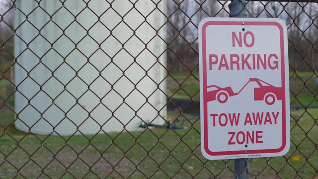 No parking tow away sign on chainlink fence