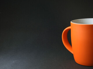Simple beautiful orange cup with handle on dark background