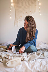 Smiling woman reading her diary on bed
