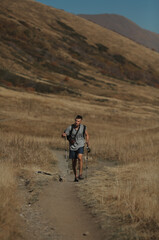 Naklejka premium man with hiking poles in the mountains