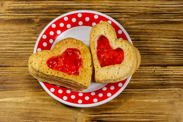 Obraz na płótnie Canvas Heart shaped puff cookies with jam on a wooden table. Top view. Dessert on Valentine`s Day