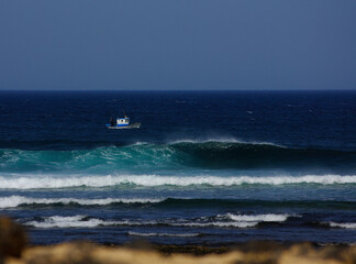Boat fishing in the Atlantic ocean near the rocky shore.