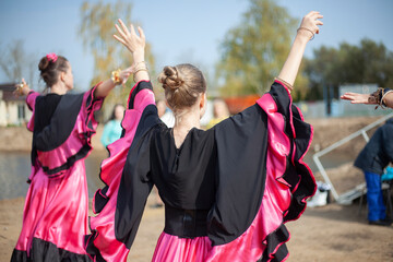 Gypsy dance in black dress. Girl dancing folk dance on the street. Filming of dancing girls from the back.