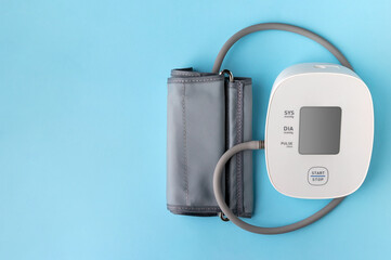 Automatic blood pressure monitor on blue background. Medical electronic tonometer with copy space