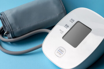 Automatic blood pressure monitor on blue background. Medical electronic tonometer. Closeup view