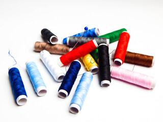 Sewing thread in different colours on white background.