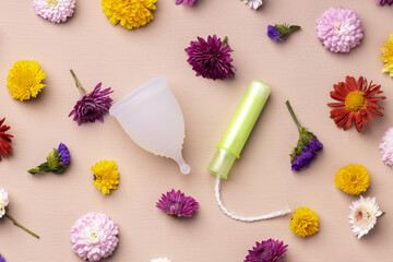 Obraz na płótnie Canvas Menstrual cup and tampons on floral pattern background