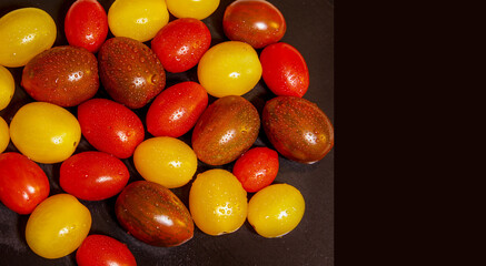  Cherry Tomatoes . Copy Space. Colorful wet cherry tomatoes  on a black background.  Room to write. Stock Image.