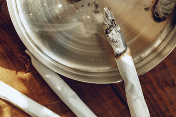 Lighted cigarette in a metal ash tray close up