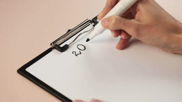 girl's hand close up with a marker written A4 paper 2021 New Year makes