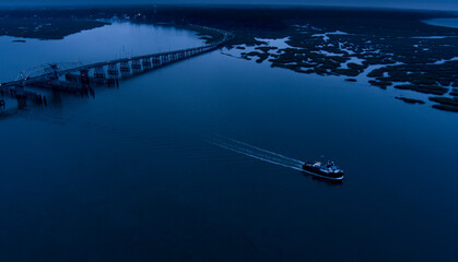 Aerial view of a small commercial ship going past the small town of Beaufort, South Carolina at night