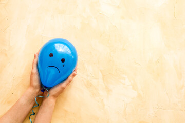 Sadness emotion face on balloon - depression mood background. Top view, copy space